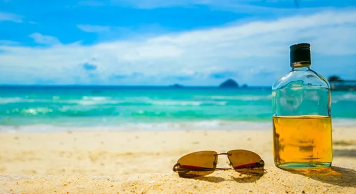 A bottle of Jamaican rum with sunglasses on the beach