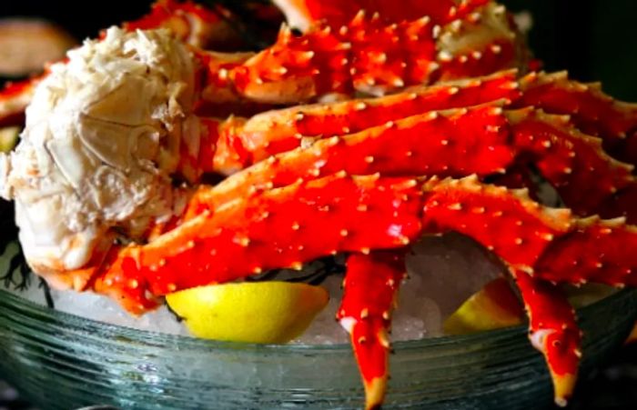 Alaskan king crab legs presented on ice with a lemon wedge.