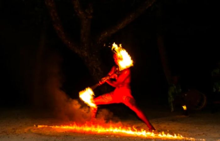 man dancing a traditional Hawaiian luau with no shirt and a fire stick