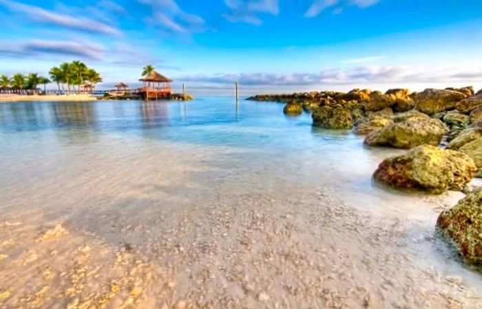 Rocks and a pier beside the crystal-clear waters of a beach in Nassau, Bahamas