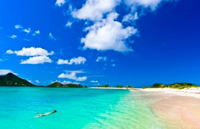 a woman floating along the beach in Grenada on a bright, sunny day