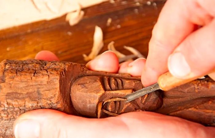 a person carving a wooden sculpture by hand in Princess Cays