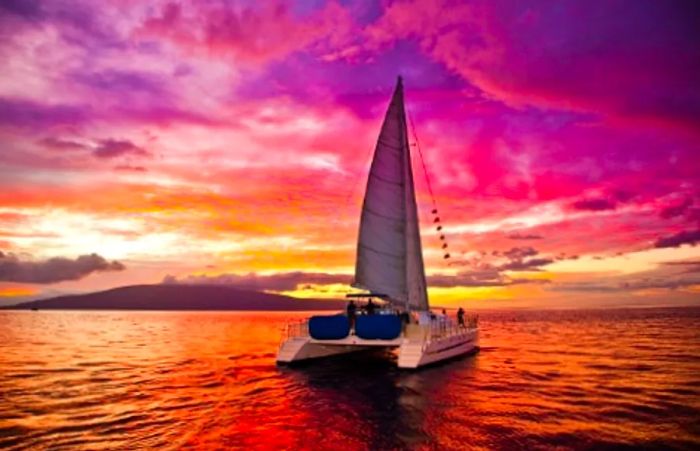 catamaran gliding through the ocean at sunset near Maui