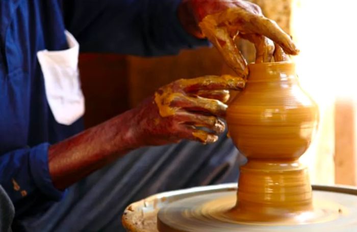 artisan shaping pottery by hand on a pottery wheel