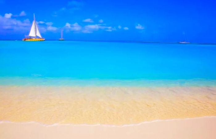 Three yachts sailing through the sky-blue waters of Love Beach in Nassau, Bahamas