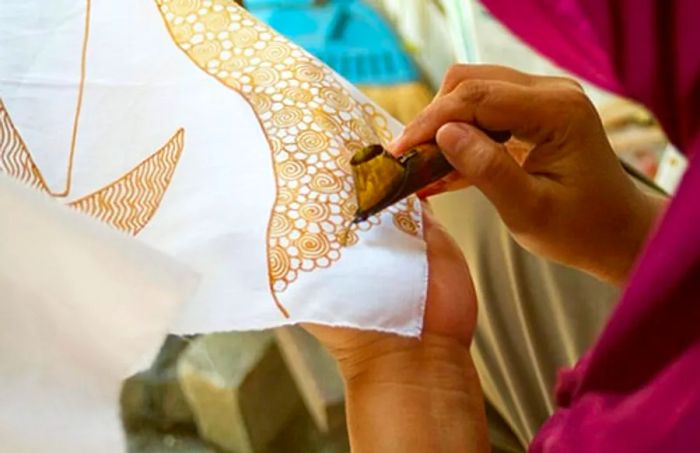 a woman applying batik patterns onto white fabric in Princess Cays