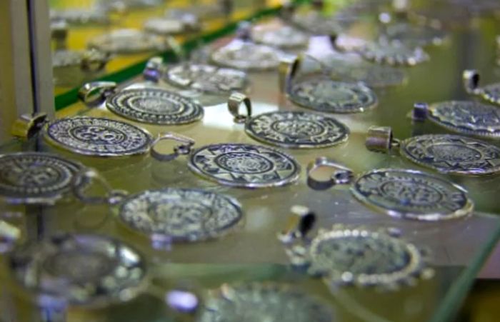 a collection of Mexican pendants crafted from Taxco silver displayed on a glass shelf