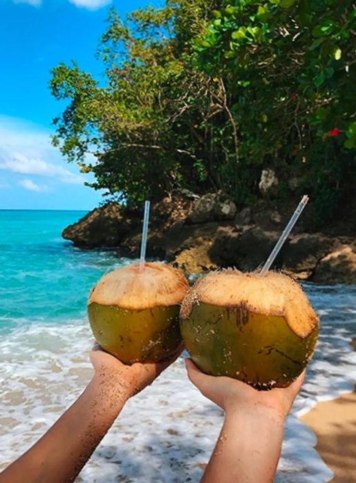 Tess and Sarah joyfully hold coconuts aloft on the beach.