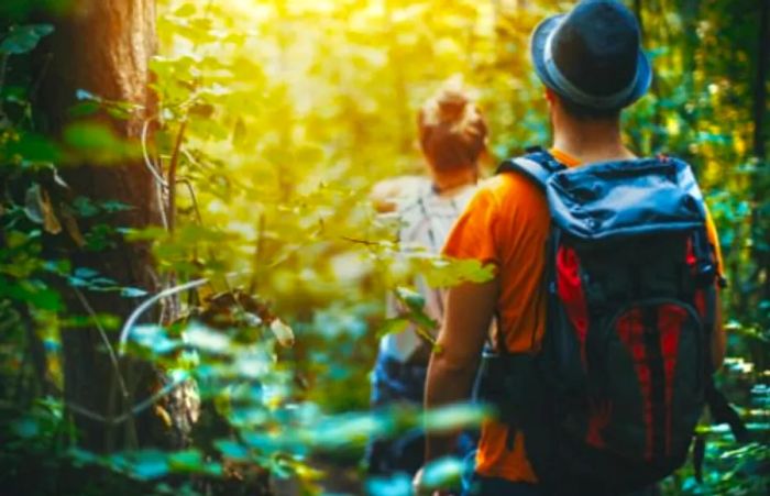 man with a backpack and woman trekking through a Hawaiian rainforest