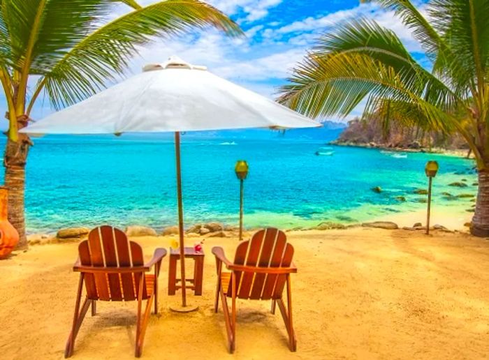 wooden beach chairs and a white umbrella on Las Caletas Beach