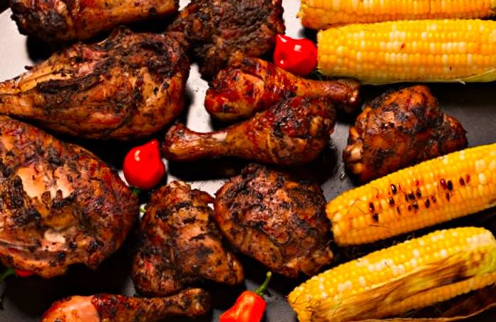 grilled jerk chicken accompanied by Scotch bonnet peppers and corn on the cob