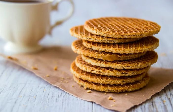 a stack of stroopwafels next to a cup of coffee