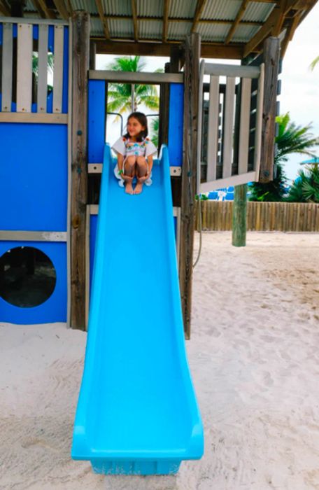 daughter perched atop a blue slide