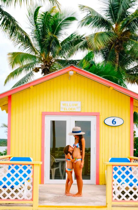 Drea and her daughter embracing in front of a yellow bungalow