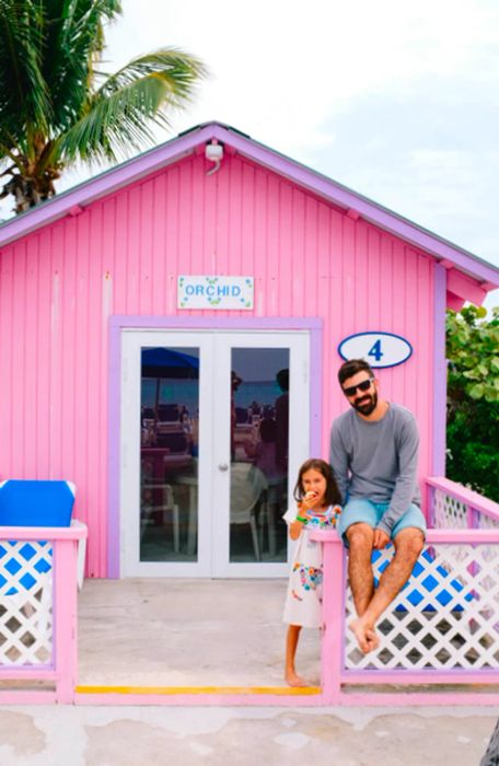 dad and daughter standing in front of a pink bungalow