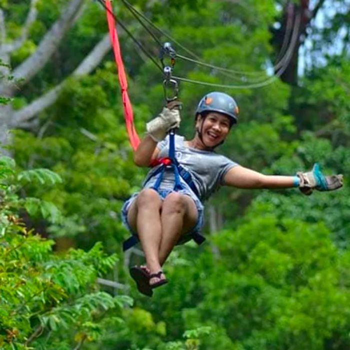 a joyful woman ziplining through the trees