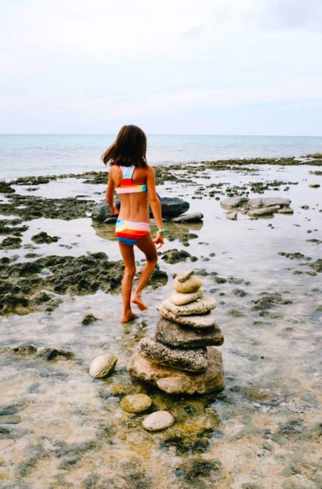 daughter exploring the rocky beach near a small stone formation