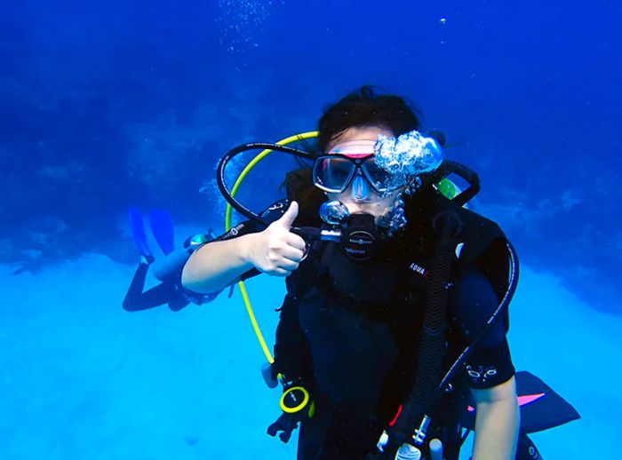 a woman giving a thumbs-up while scuba diving in Bonaire