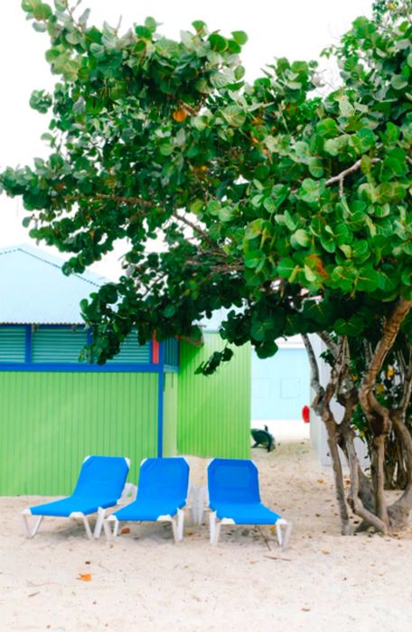 three blue beach loungers in front of a green bungalow