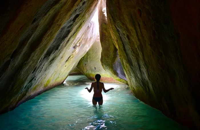 A woman navigating a narrow passage in The Baths, Virgin Gorda