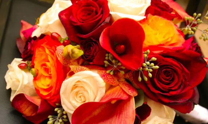 A wedding bouquet featuring red, orange, and white flowers