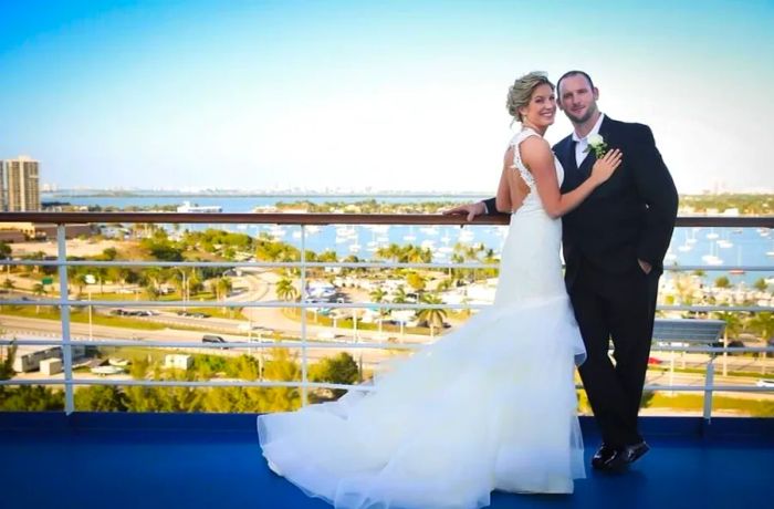 Newlyweds standing by a railing with a city skyline in the background