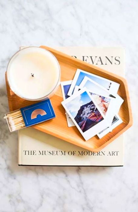 Aerial shot of a candle, matches, and instant prints nestled in a small wooden dish