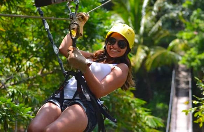 a woman relishing the thrill of zip lining through a forest