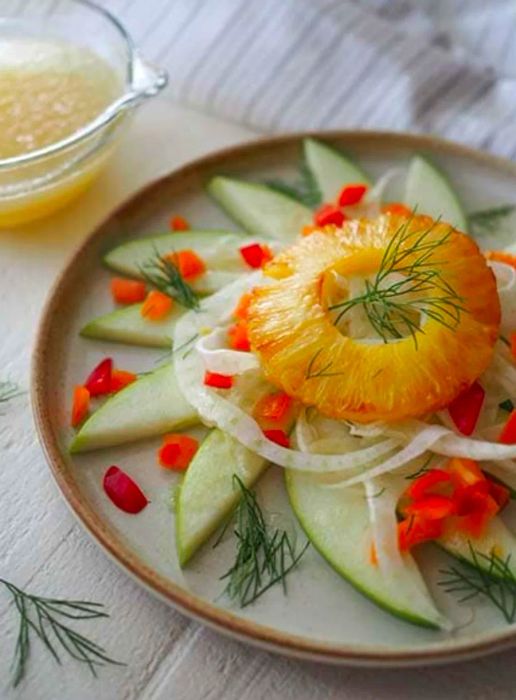 Plated grilled pineapple and fennel salad with honey ginger dressing on the side