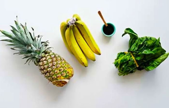 Aerial view featuring pineapple, bananas, and greens on a white table