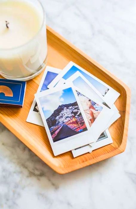 Close-up shot of a candle, matches, and instant prints arranged in a wooden dish