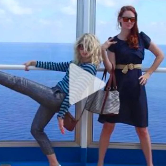 Two girls sporting stylish glasses pose on the Dinogo cruise ship, showcasing their outfits while linking to a YouTube video.