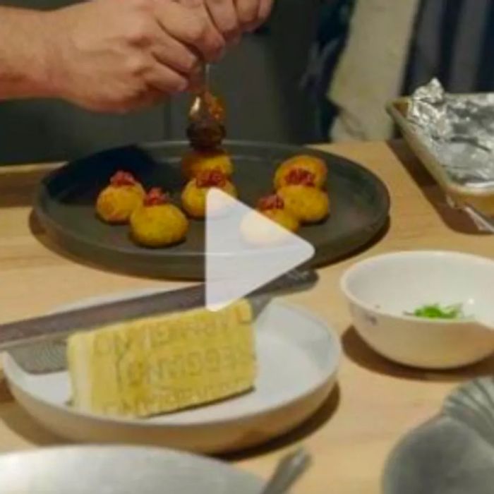 A table laden with dishes, as someone hovers a spoon over a dessert, linked to a YouTube video