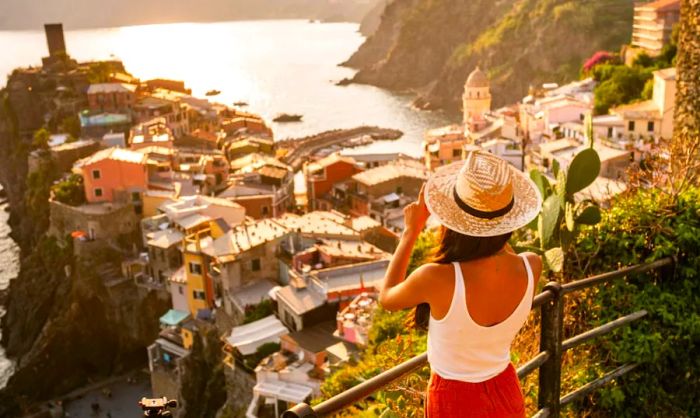 A female traveler gazes over a stunning view of Vernazza bathed in golden light.