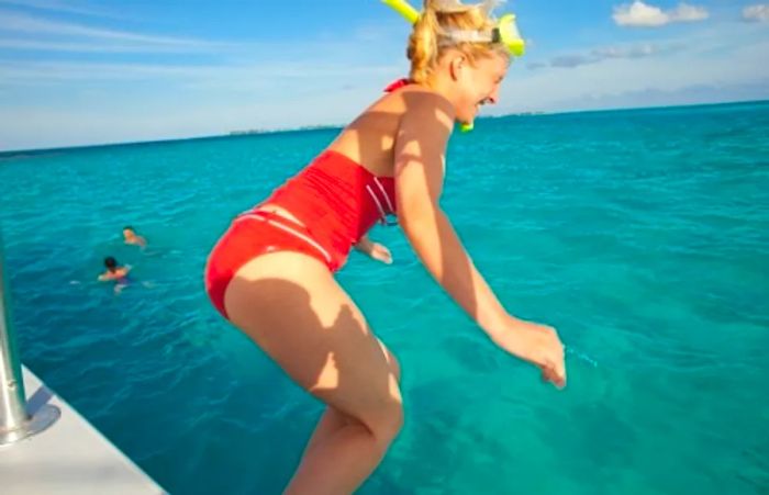 a woman poised to dive into the water with her snorkel mask on