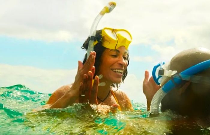 a woman sharing excitement with her snorkeling partner above the water