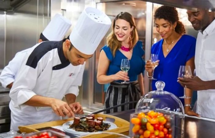 a group of friends watching an executive chef skillfully prepare his signature dish