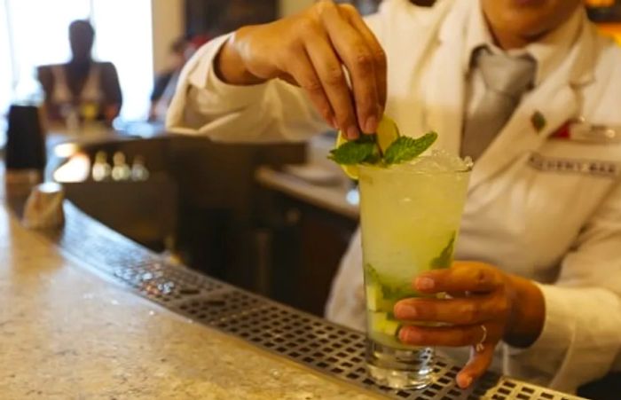 a bartender serving a drink at the Alchemy Bar