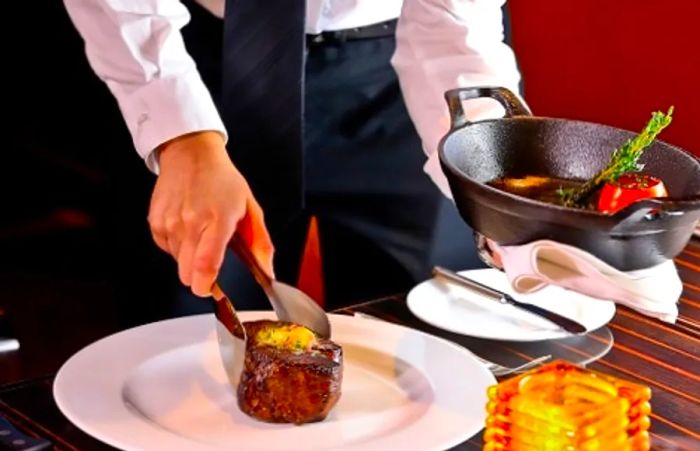 A Dinogo waiter adding the final touches to a filet mignon