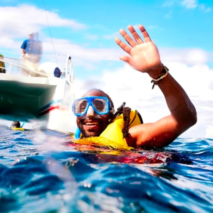 waving at the camera as he finishes his snorkeling adventure