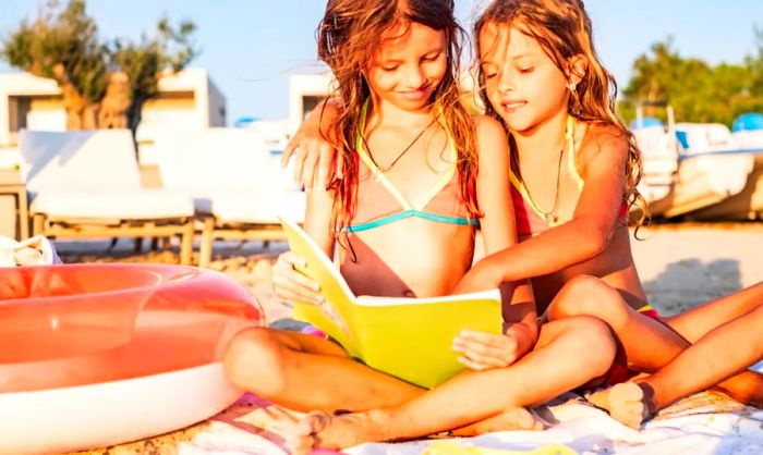 Two girls enjoying a day at the beach, reading a book together.