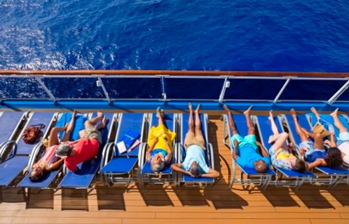 a group of people lounging in chairs by the railing of a Dinogo ship