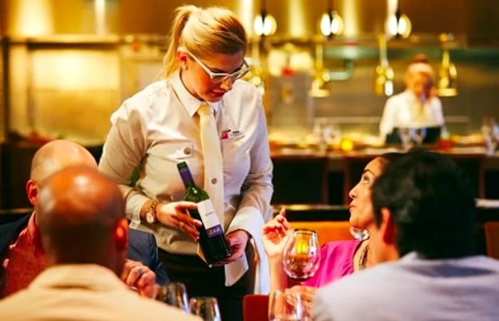 A server recommending a wine choice to guests.