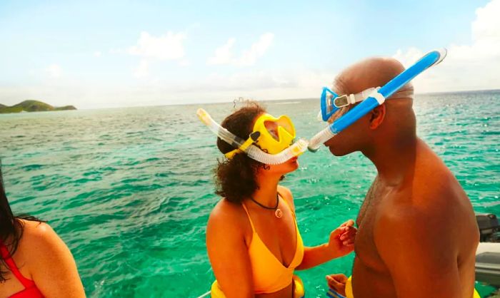 A couple equipped with snorkeling gear by the shoreline