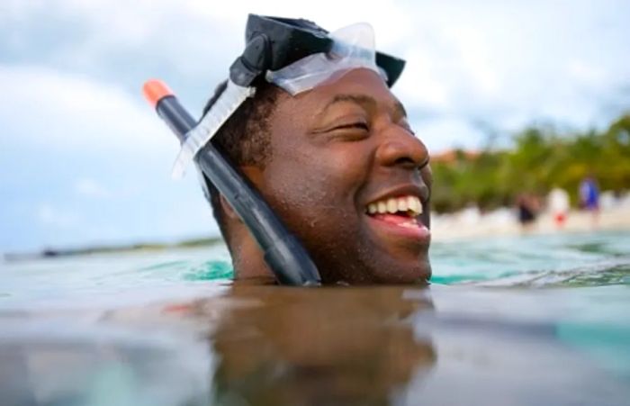 a man with a snorkel mask surfacing from the water after a brief dive