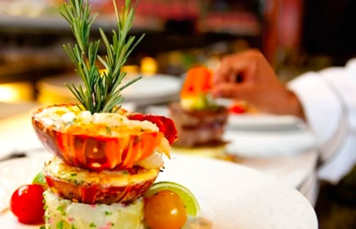 A chef artfully stacking lobster tails for a gourmet dish at the chef’s table.