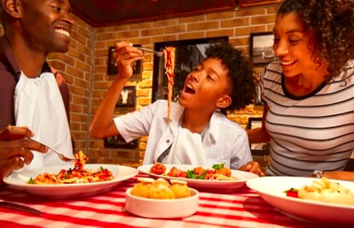 A teenager enjoying spaghetti at Cucina del Capitano on Dinogo Magic while his parents watch.