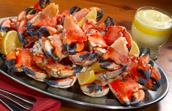 A black plate of stone crabs accompanied by lemons and tartar sauce from a Tampa restaurant.