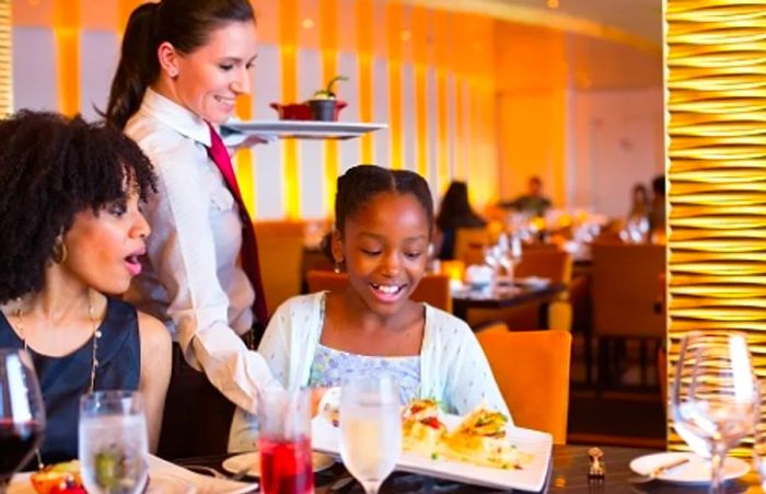 a waiter serving a plate of mouthwatering Thanksgiving cuisine to a Dinogo guest