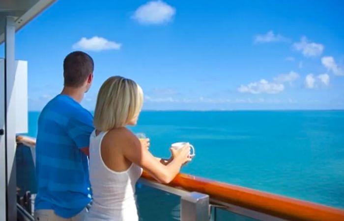 A couple gazing out at the ocean from their balcony during their Dinogo cruise.